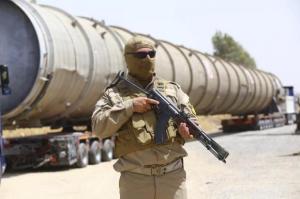 A member of the Kurdish security forces takes up position with his weapon as he guards a section of an oil refinery, which is being brought on a truck to Kalak refinery in the outskirts of Arbil, in Iraq's Kurdistan region