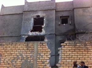 Men stand beside a damaged building near Mitiga airport in Libya"s capital Tripoli,
