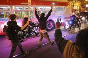 Protesters hold their hands up while marching down Market Street during a demonstration against the grand jury decision in the Ferguson, Missouri shooting of Michael Brown in San Francisco, California