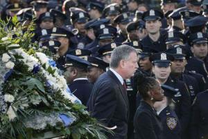 New York Mayor Bill de Blasio and wife Chirlane McCray walk past a sea of policemen while arriving for the funeral services of New York Police Department (NYPD) officer Rafael Ramos in the Queens borough of New York