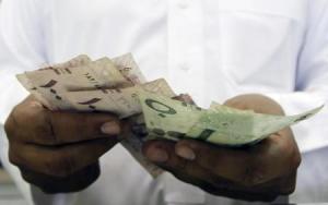 تاجر يمسك أوراق متعددة الفئات من الريال السعودي في مكة