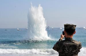A South Korean marine stands on a beach as amphibious assault vehicles (in background) approach the shore during a joint US and S.Korean military drill in Pohang, 270 km south-east of Seoul