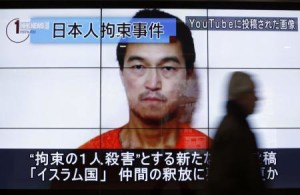 A man walks past screens displaying a television news programme showing an image of Kenji Goto, one of two Japanese citizens taken captive by Islamic State militants, on a street in Tokyo