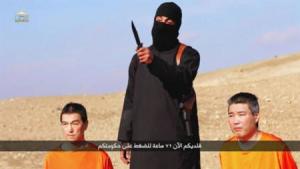 A masked person holding a knife speaks as he stands in between two kneeling men in this still image taken from an online video released by the militant Islamic State group