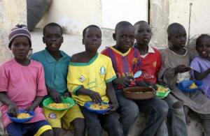 Children displaced as a result of Boko Haram attacks in the northeast region of Nigeria, sit in a row to eat a meal at a camp for internally displaced persons (IDP) in Yola, Adamawa State
