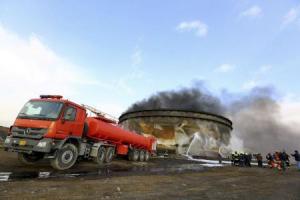 Fire-fighters work to put out a fire at a storage oil tank in the port of Es Sider