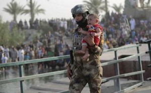 An Iraqi soldier carries a displaced kid from Ramadi on the outskirts of Baghdad