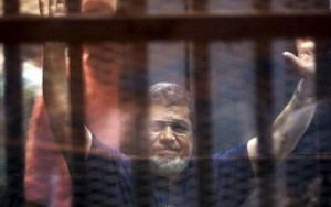Former Egyptian President Mohamed Mursi waves as he enters for his trial with other Muslim Brotherhood members at a court in the outskirts of Cairo