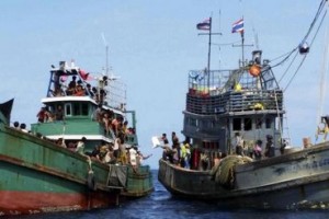 Thai fishermen (R) give some supplies to migrants on a boat drifting 17 km (10 miles) off the coast of the southern island of Koh Lipe, Thailand