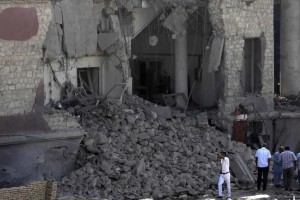 Egyptian policemen stand at the base of the crumbled facade of the Italian consulate following a blast that killed at least one person in Cairo, Egypt, Saturday, July 11, 2015. An Italian embassy official said the consulate was closed at the time of the explosion and no staff members were injured.
