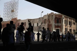 Egyptian policemen stand at the base of the crumbled facade of the Italian consulate following a blast that killed at least one person in Cairo, Egypt, Saturday, July 11, 2015. An Italian diplomat said the consulate was closed at the time and no staff members were wounded in the blast.