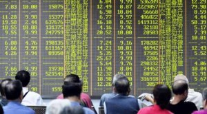 المستثمرون وهم يجلسون أمام شاشة تبين حركات السوق في شركة أوراق مالية غربي الصين