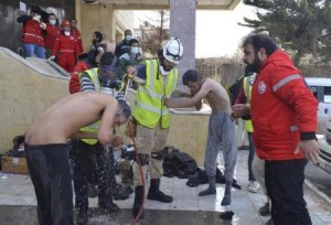 Civil Defense members spray water on rebel fighters, affected by what activists said was a gas attack, in Idlib city
