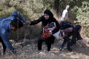 Syrian refugees walk on the fields after they crossed from Turkey to Lesbos island, Greece, 