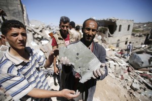 A man holds a bomb fragment from the rubble of houses destroyed by Saudi-led airstrikes in Sanaa, Yemen