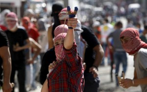 A Palestinian girl uses a slingshot to throw stones at Israeli troops during clashes in the West Bank city of Bethlehem