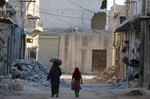 Civilians walk past damaged buildings in the rebel-held al-Sheikh Said neighbourhood of Aleppo, Syria 