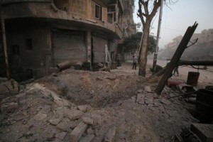 A man inspects damage near a hole in the ground after airstrikes on the rebel held al-Ansari neighbourhood of Aleppo, Syria 