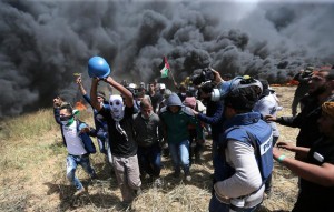 فلسطينيون أثناء إسعافهم للصحفي ياسر مرتجى وسط اشتباكات مع القوات الاسرائيلية بالقرب من الحدود مع القطاع 